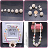 A collection of white pearl beads and a finished pearl necklace displayed on a photo frame.