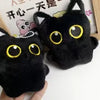 A pair of black cat plush toys with yellow eyes displayed next to a wooden frame.