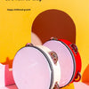 Pink and red hand-held tambourines with metal jingles displayed against a yellow background.