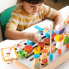 A young child is playing with a wooden BBQ playset featuring grill and food matching game pieces.