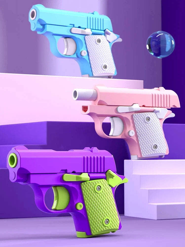 A collection of three colorful fidget pistol toys in purple, pink, and blue, displayed on stacked white platforms.