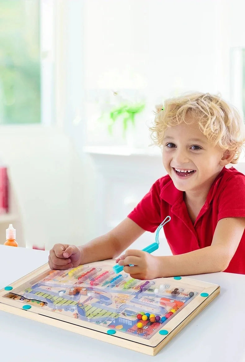 A smiling toddler is playing with a wooden magnetic color sorting maze puzzle board.
