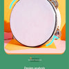A close-up of a white felt tambourine with metal jingles, resting on an orange surface.