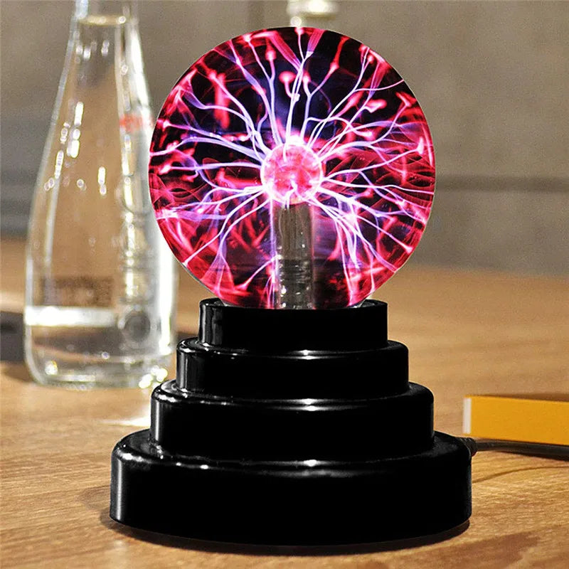 A glowing plasma ball lamp with vibrant pink and purple electrical discharges on a black base.