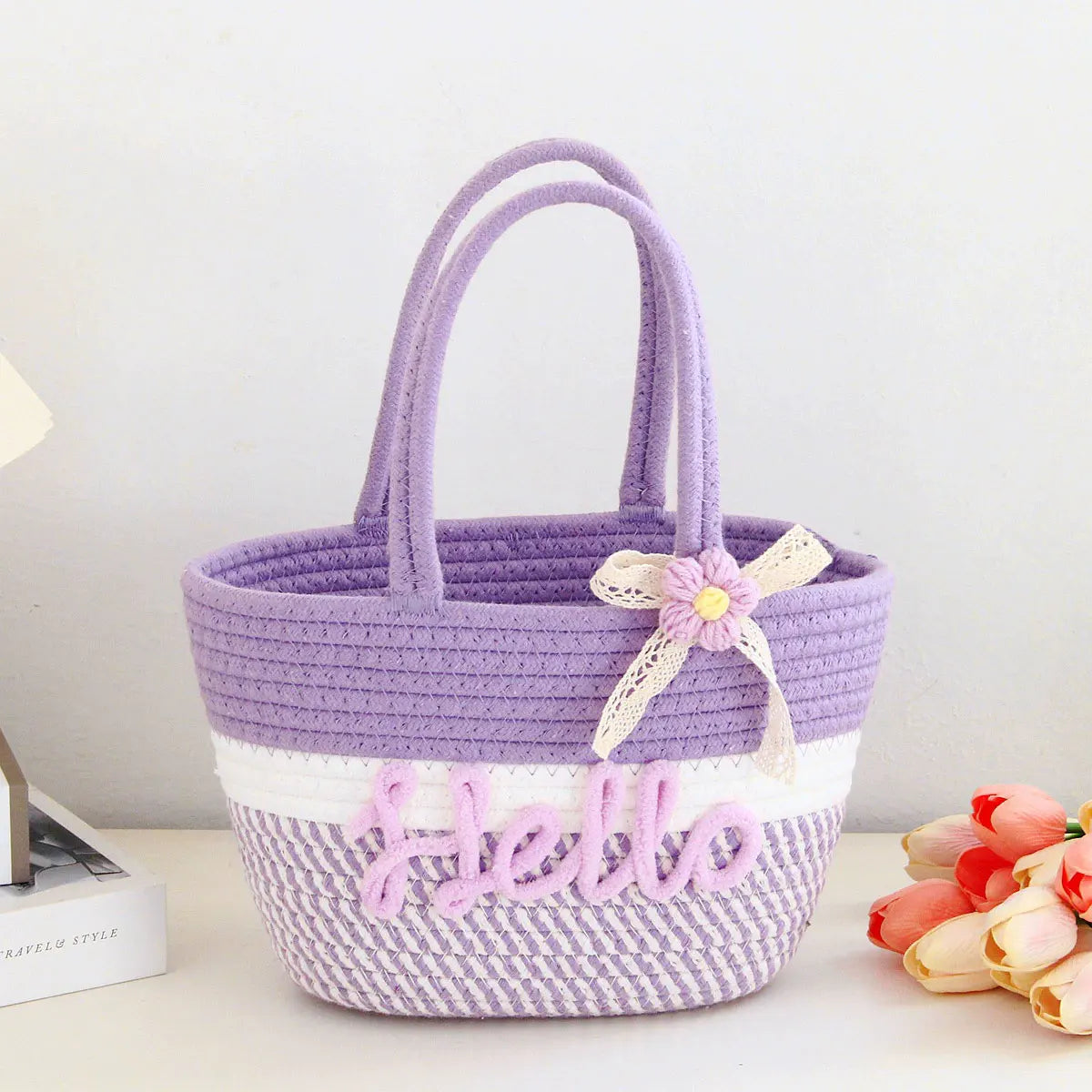 A purple and white braided cotton tote bag with the word hello embroidered on the front.
