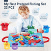 A toddler is playing with a pretend fishing set featuring 22 pieces including fish, cups, and counting items on a blue mat.