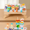 A wooden BBQ tripod playset with various food items and grill tools for pretend play.