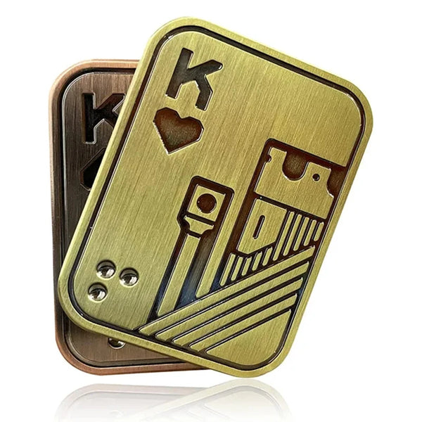 A brass metal fidget spinner toy with a skull design and engraved letters on a wooden base.