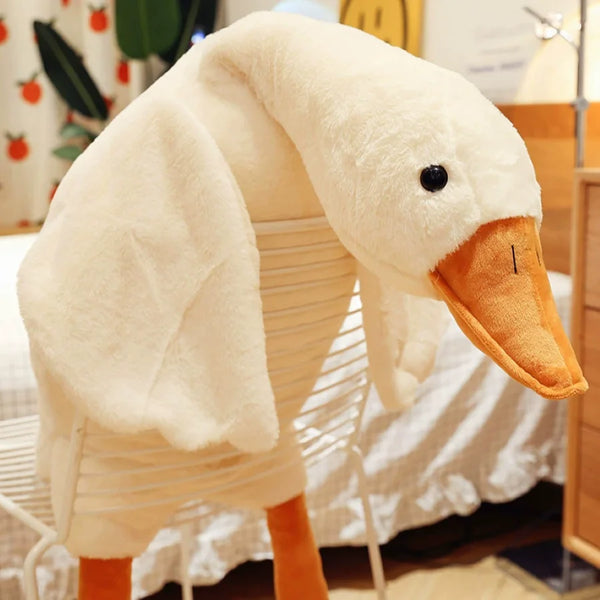 Un peluche de pato y ganso con pico naranja y plumas blancas.