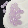 A pile of light purple glass round beads for jewelry making displayed in a white dish.