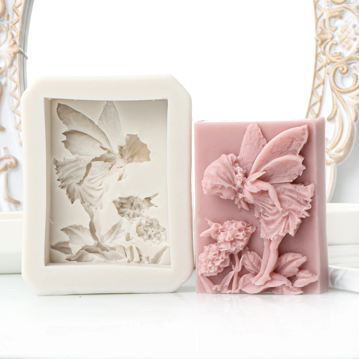 A pink silicone soap mold featuring a 3D design of a flower, rose, and butterfly.