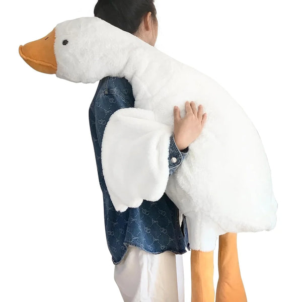 Una persona sostiene un peluche blanco de pato o ganso con pico naranja y ropa de mezclilla azul.