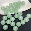 A collection of light green glass round beads arranged on a white dish and a dark surface.