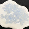 A pile of light blue and clear glass round beads for jewelry making on a white surface.