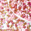 Assortment of pink, red, and white acrylic beads with gold accents for jewelry making
