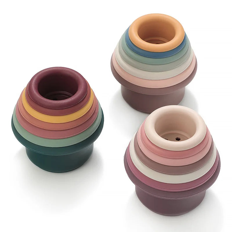A stack of five silicone cups in pastel and earthy tones, showing various shades of pink, green, and brown.