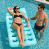 A woman relaxing on a light blue inflatable pool float with a headrest in clear water.