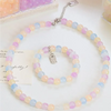 A string of dual-color glass round beads, featuring pink and blue shades, is displayed on a white surface.