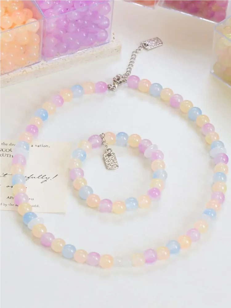 A string of dual-color glass round beads, featuring pink and blue shades, is displayed on a white surface.