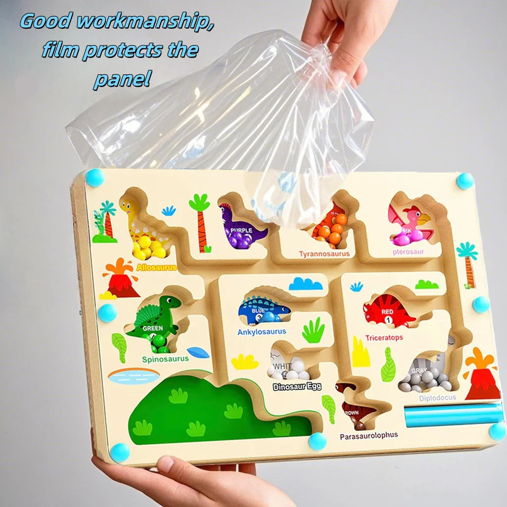 A hand holds a wooden magnetic color sorting maze puzzle board with various dinosaur figures and a clear plastic film protect