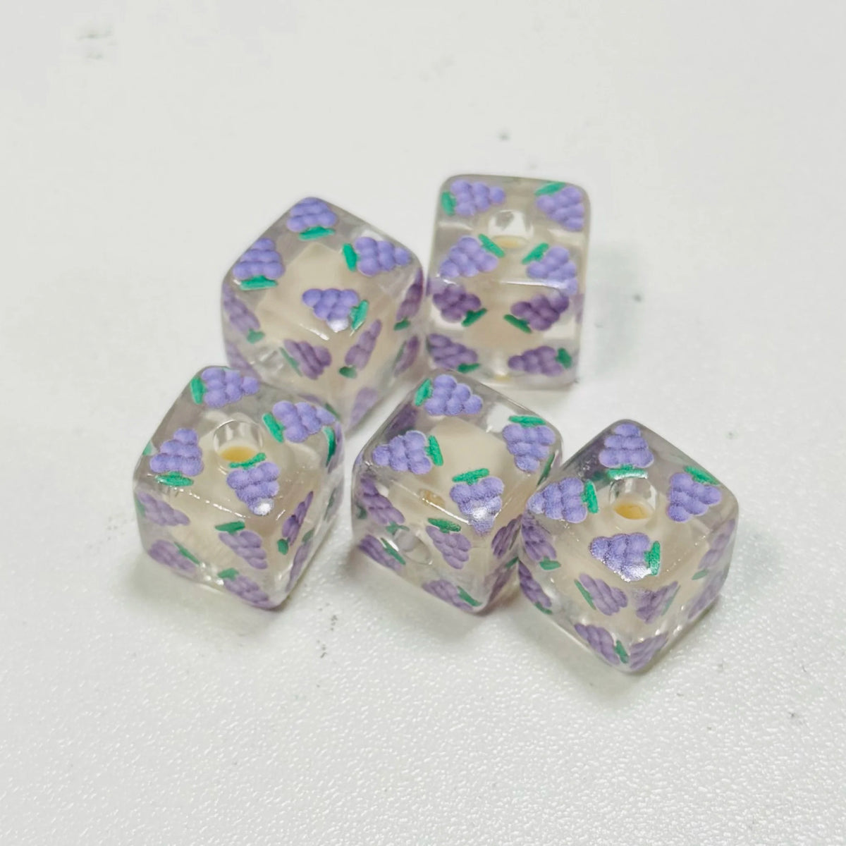 Several translucent purple and white floral square resin beads for DIY jewelry making