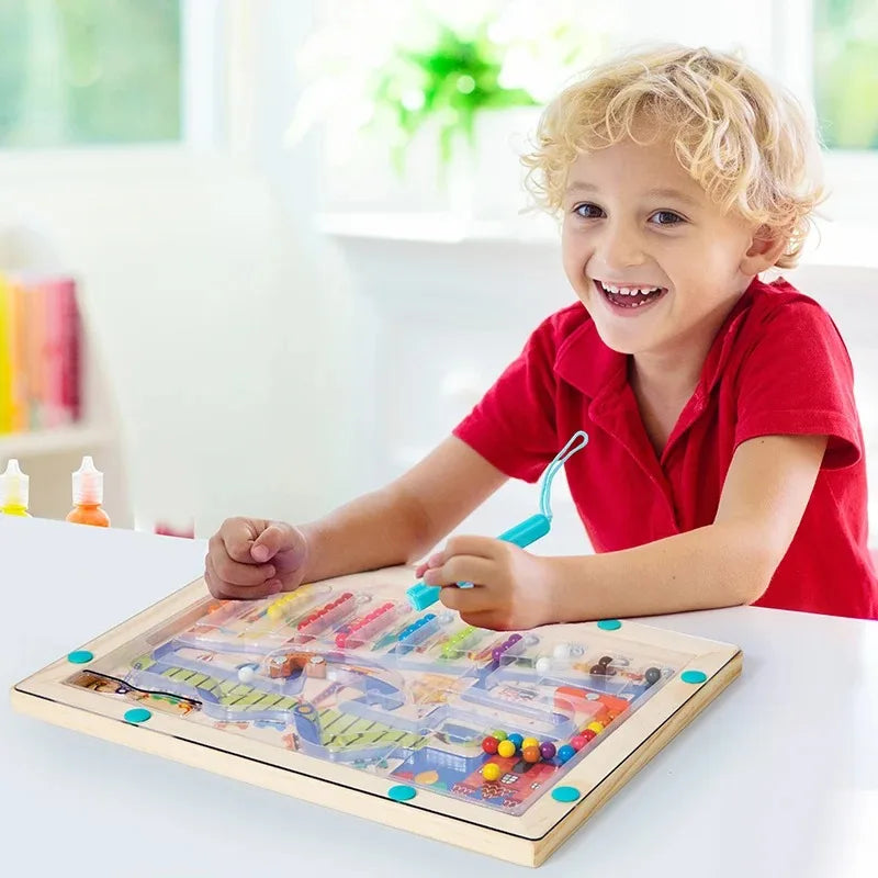 A smiling toddler is interacting with a wooden magnetic color sorting maze puzzle board.