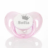 A pink baby pacifier with a crown design and storage case labeled Sofia