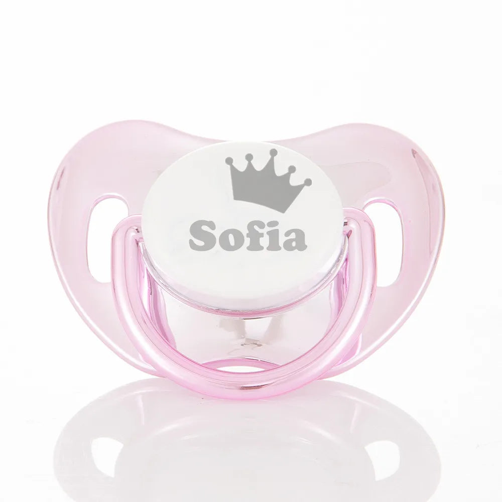 A pink baby pacifier with a crown design and storage case labeled Sofia