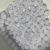 A close-up view of a 50-pack of dual-color glass round beads for jewelry making, featuring light purple and clear beads.