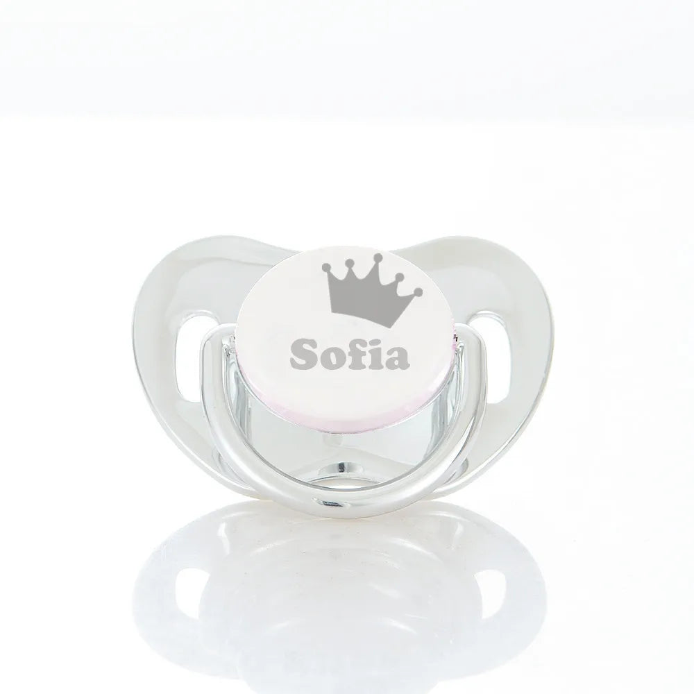 A clear storage case for a baby pacifier featuring a crown design and the name Sofia engraved on the cap.