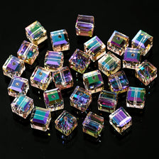 A collection of faceted crystal cubes in various sizes and colors, used for jewelry making.