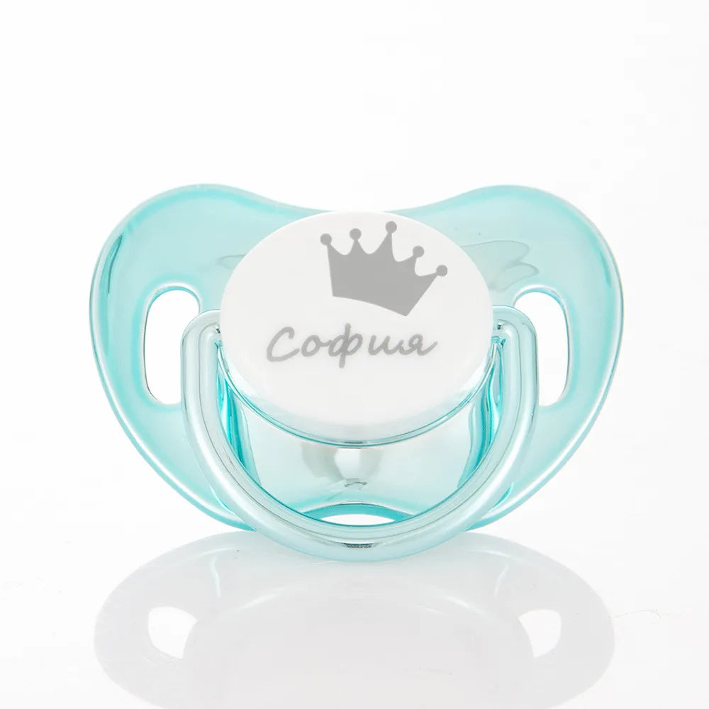 A clear silicone baby pacifier with a crown design and storage case, featuring the name Sofia.