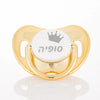 Gold-colored pacifier storage case with a white pacifier featuring a silver crown design