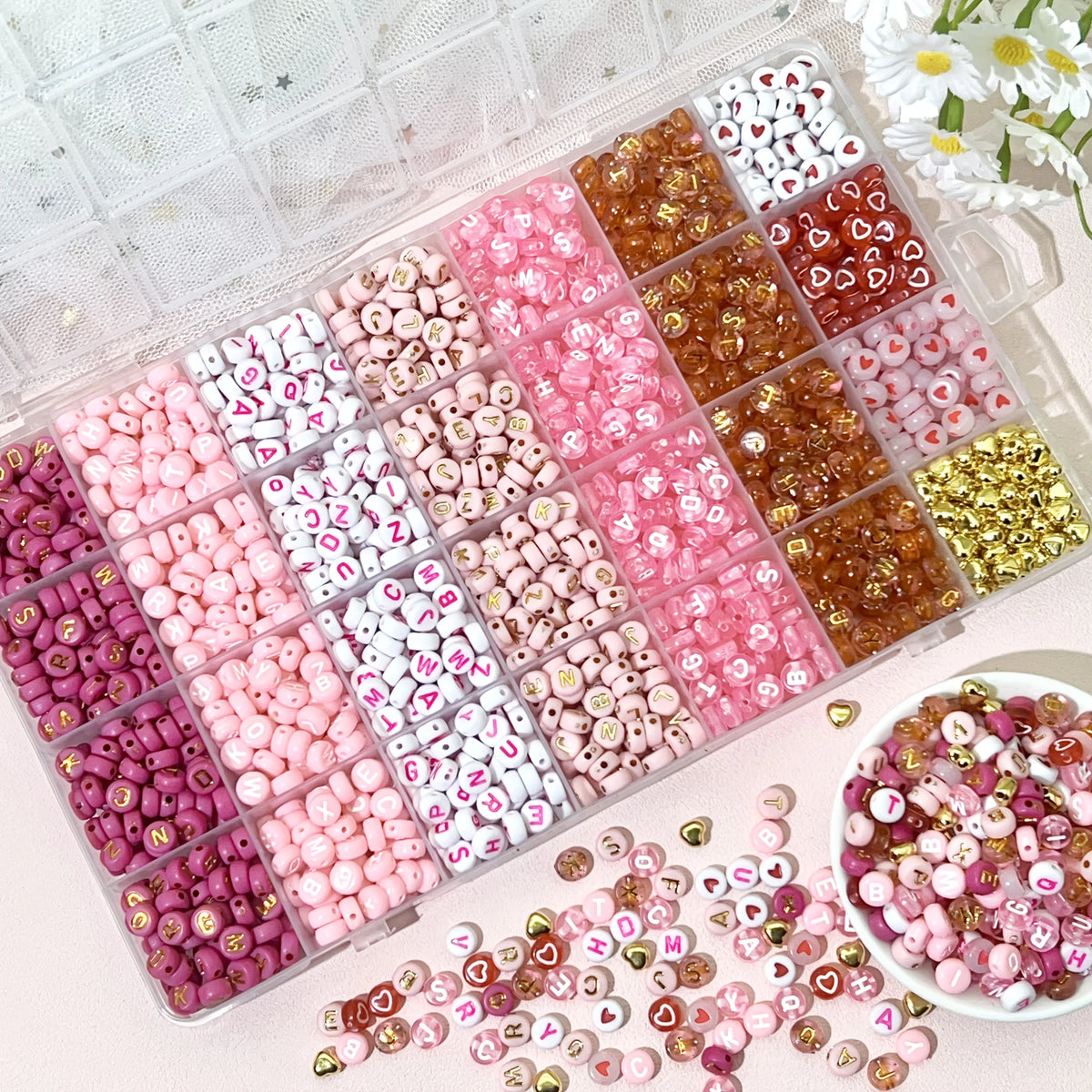 A variety of pink, red, and white acrylic beads with gold accents are displayed in a clear plastic box.