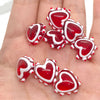 A collection of red heart-shaped lampwork glass beads for jewelry making displayed on a hand.