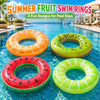 Four colorful fruit-inspired swim rings floating in clear blue water.