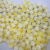 A close-up view of a 50-pack of dual-color glass round beads, featuring pale yellow and translucent white shades.