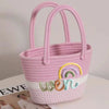 A pink braided cotton tote bag with a rainbow design and the word women on it.