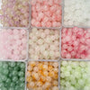 A collection of dual-color glass round beads in various shades of pink, white, green, and amber for jewelry making.