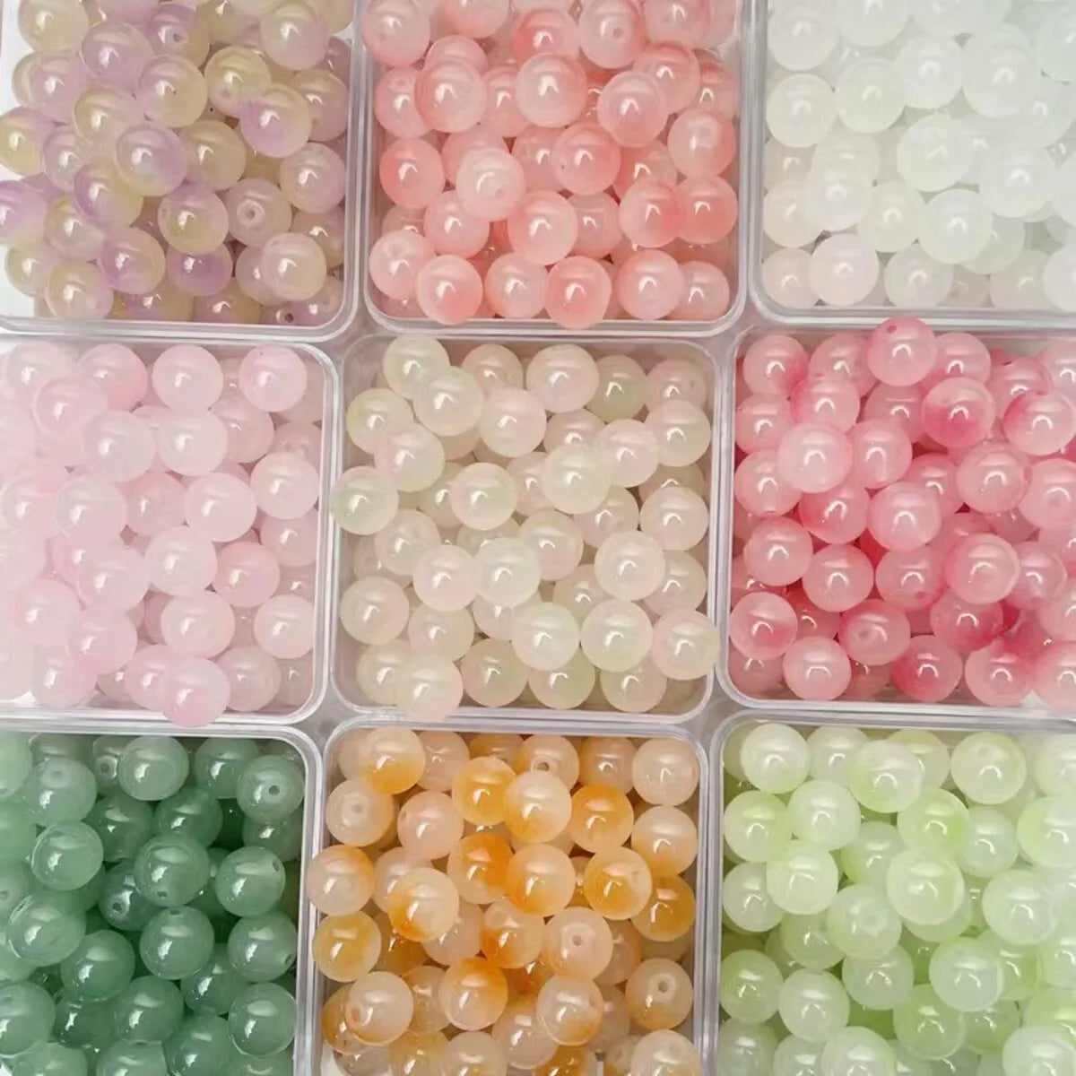 A collection of dual-color glass round beads in various shades of pink, white, green, and amber for jewelry making.