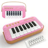 A pink mini piano keyboard with a white and black key layout and a separate numbered practice sheet.