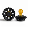 A black silicone pacifier with a yellow tip and a flower-like design.