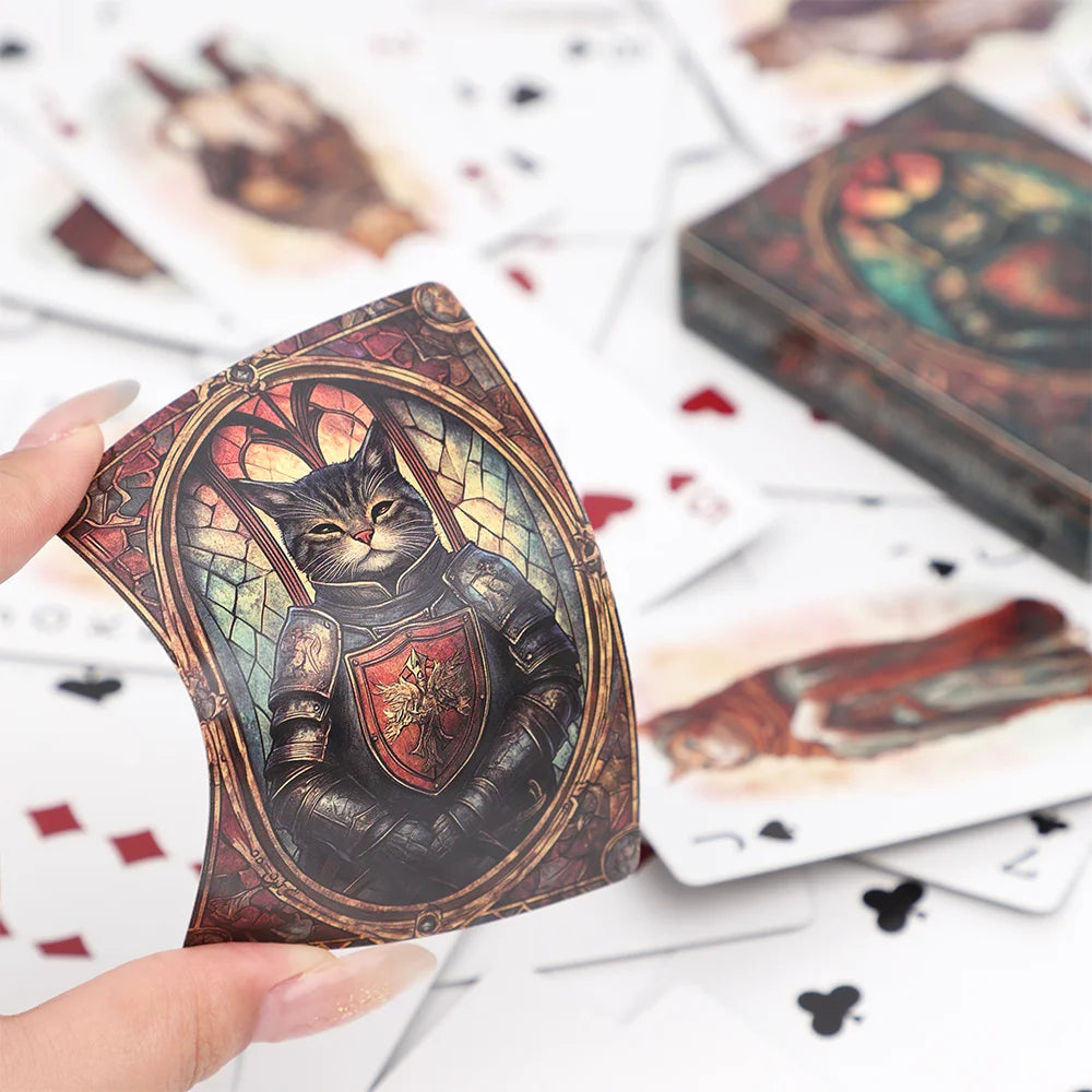A hand holds a vintage cat illustration playing card deck with a dark, ornate design on a white background.