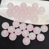 A collection of pink and clear glass round beads for jewelry making displayed on a white oval plate.