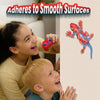 A girl and a boy are playing with a red gecko wall crawler robot against a light background.