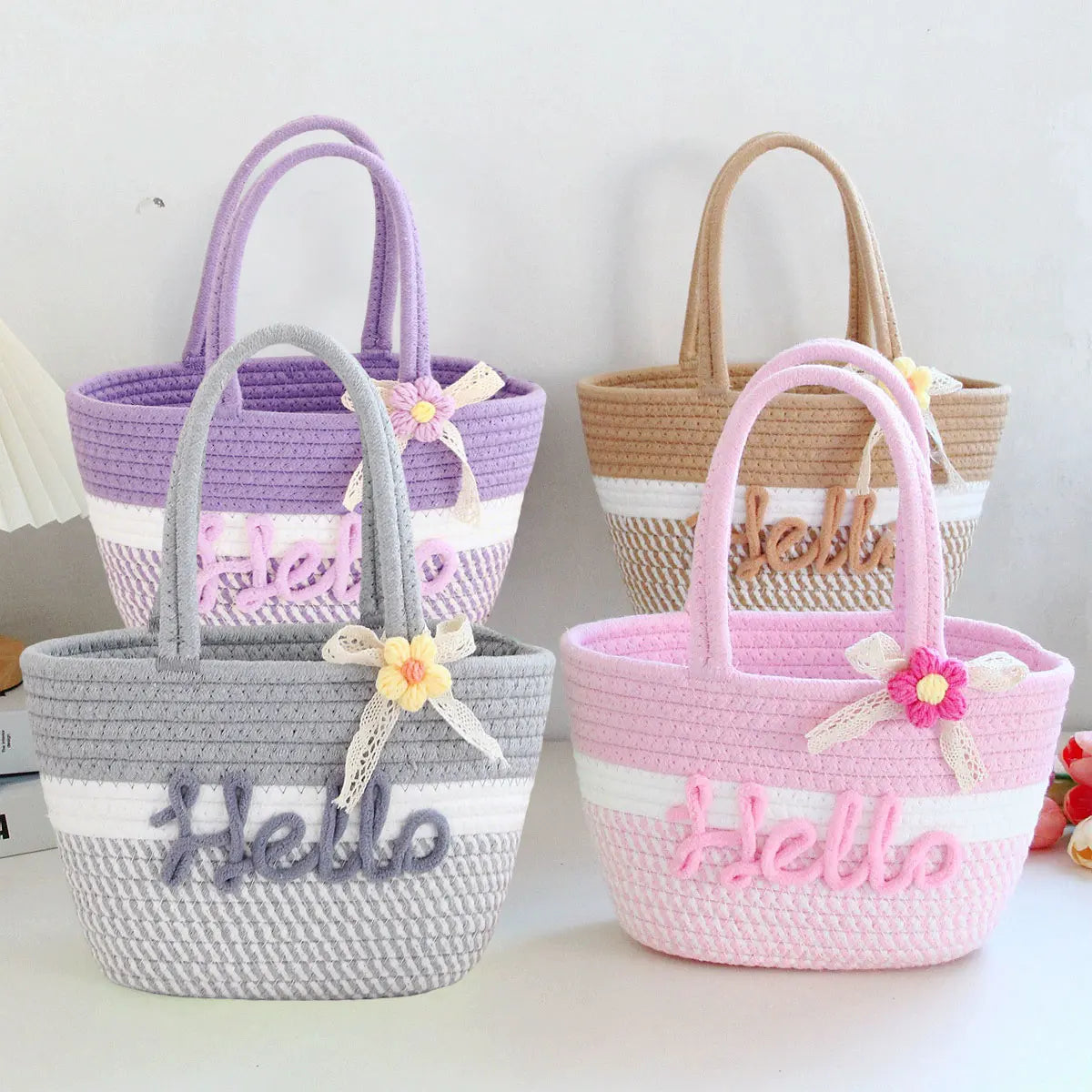Three braided cotton tote bags in purple, beige, and pink with floral accents.