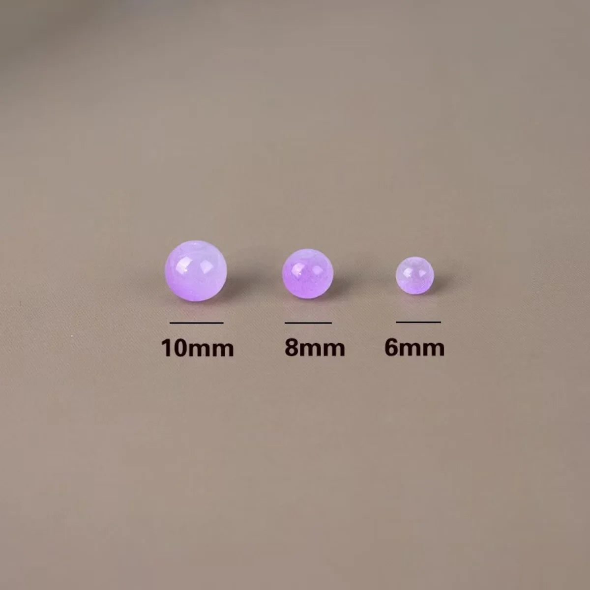 Three round glass beads of varying sizes (10mm, 8mm, and 6mm) are displayed on a neutral background.