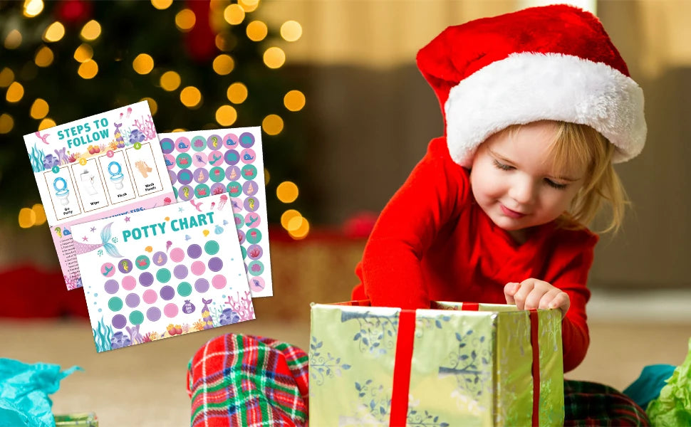 A toddler in a red shirt is looking at a colorful potty chart and a wrapped gift.