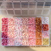 Assortment of pink, red, and white acrylic beads with gold accents for jewelry making