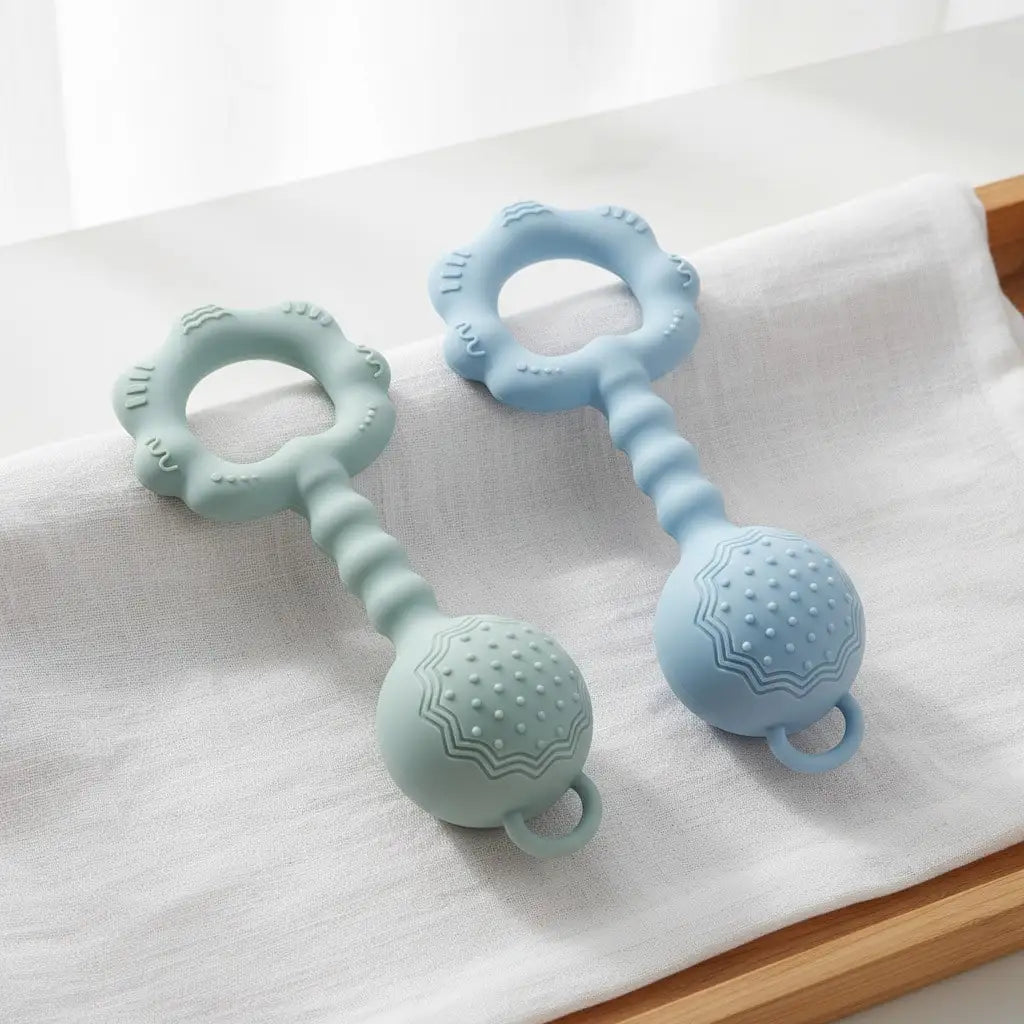 Ein Set aus hellblauen Silikon-Babymanschetten und -Käuerlernspielzeug auf einem weißen Tuch.
